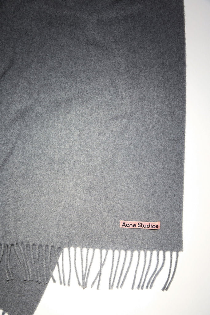 The Fringe Wool Scarf 217 by Acne Studios is a signature fringed scarf with a pink Acne Studios label crafted from midweight wool in dark grey melange