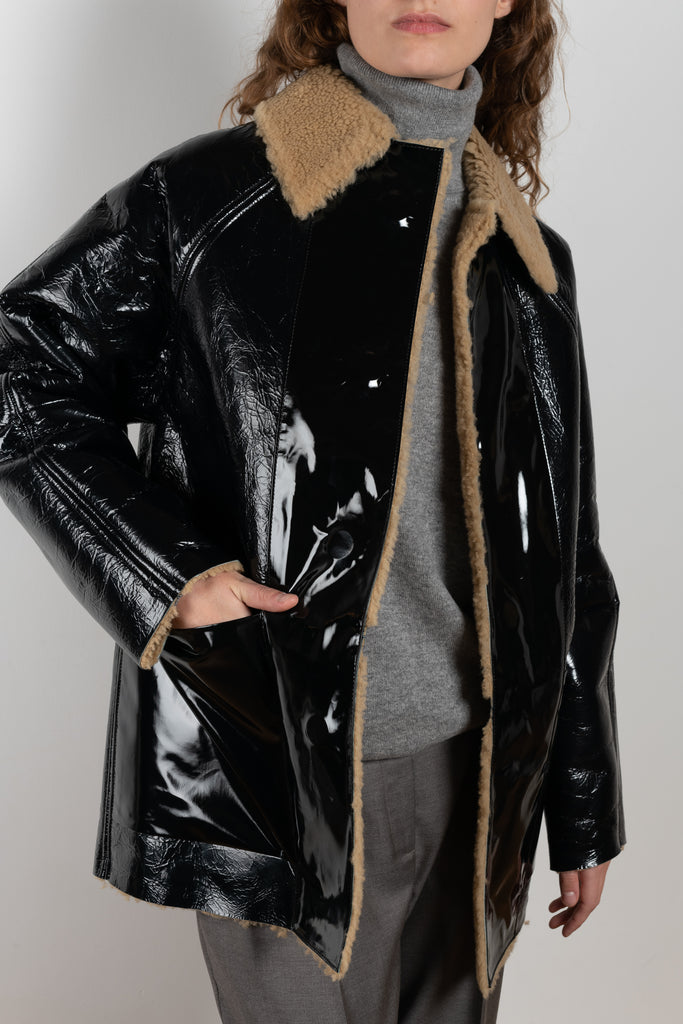 The Reversible Shearling Coat by KASSL Editions is a bold black lacquer coat fully lined with shearling. The coat is reversible due to the magnetic closure, making it the ultimate versatile wardrobe staple