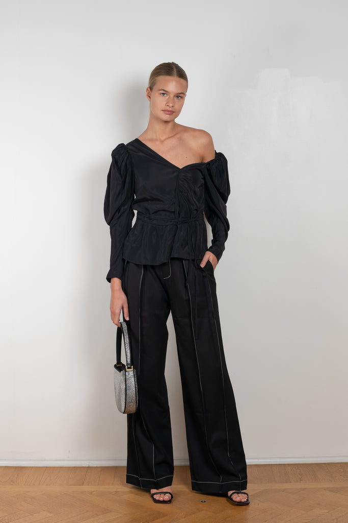 The Fiona Top by Rejina Pyo is a one-shoulder top with long puff sleeves, a tie detail to cinch the waist and exaggerated cuffs