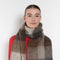 Woman wearing a plaid scarf with a plain background