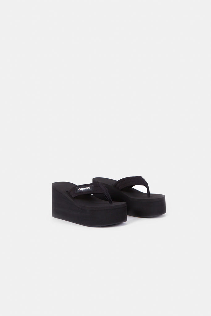 The Branded Wedge Sandal by Coperni is a signature black wedge sandal with lightweight platform soles
