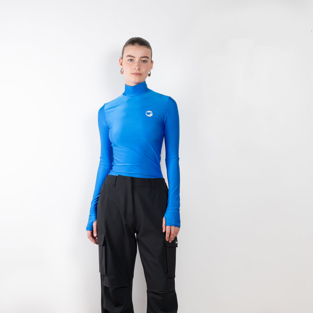 The Tight High Neck Top by Coperni is a signature fitted top in electric metallic blue with a silver C Logo on the chest and thumb holes
