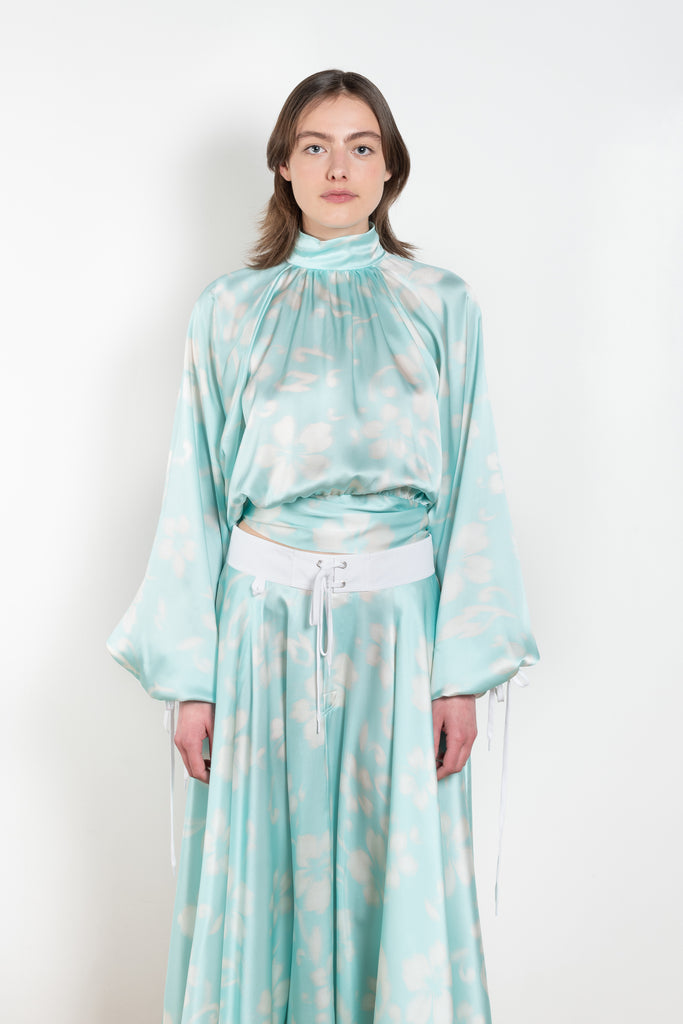 The Tracy Silk Blouse by Julie Kegels is a silk wrap top in aqua with a Hawaïan floral print and contrasting cuffs