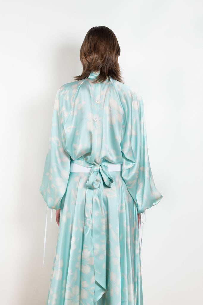 The Tracy Silk Blouse by Julie Kegels is a silk wrap top in aqua with a Hawaïan floral print and contrasting cuffs
