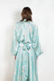 The Tracy Silk Blouse by Julie Kegels is a silk wrap top in aqua with a Hawaïan floral print and contrasting cuffs