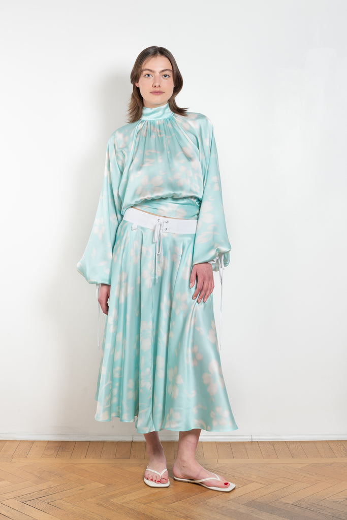 The Tracy Silk Blouse by Julie Kegels is a silk wrap top in aqua with a Hawaïan floral print and contrasting cuffs