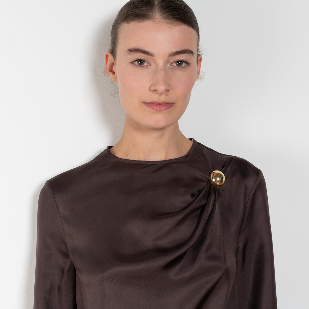 The Azae Blouse by Loulou Studio is a refined silk twill blouse with a draped detail and hardware embellishment