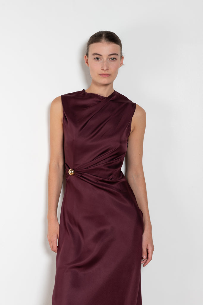 The Roan Dress by Loulou Studio is an elegant evening dress with a draped detail and hardware embellishment in a fluid silk twill