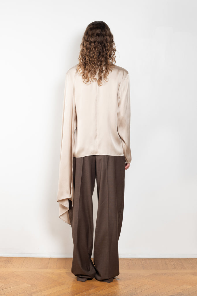 The Silk Shirt by Magda Butrym is a long-sleeve silk blouse with a round neck and carefully draped fabric that gives way to a dramatic cape that sweeps off the shoulder