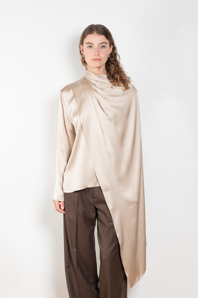 The Silk Shirt by Magda Butrym is a long-sleeve silk blouse with a round neck and carefully draped fabric that gives way to a dramatic cape that sweeps off the shoulder