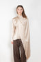The Silk Shirt by Magda Butrym is a long-sleeve silk blouse with a round neck and carefully draped fabric that gives way to a dramatic cape that sweeps off the shoulder