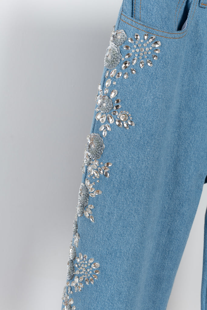 The Crystal Flower Embroidered Denim 12 by Magda Butrym is a relaxed wide leg light blue denim with sequin and gem embroidered detailing down the legs, featuring flower details