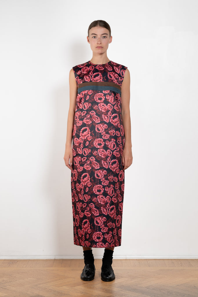 The Long Shift Dress by Meryll Rogge is a sleeveless shift dress crafted in floral scuba satin, featuring a round neckline and a contrasting ribbon detail.