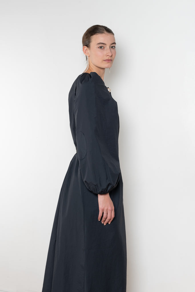 The Grand Bazaar Dress by Nackiye is a signature dress with shawl shoulder feature, two pockets, front slit and a belt, and the classic double pearl neck pin 