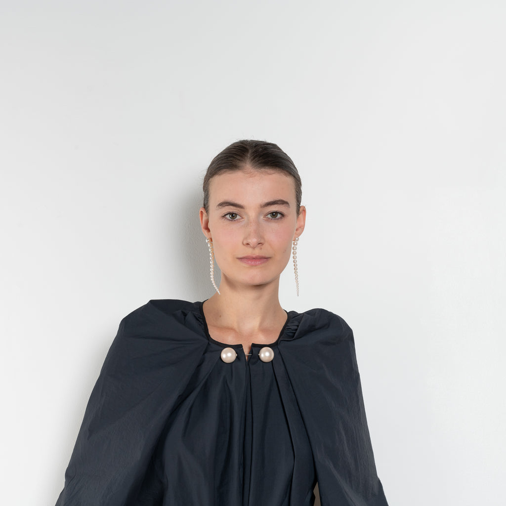 The Grand Bazaar Dress by Nackiye is a signature dress with shawl shoulder feature, two pockets, front slit and a belt, and the classic double pearl neck pin 