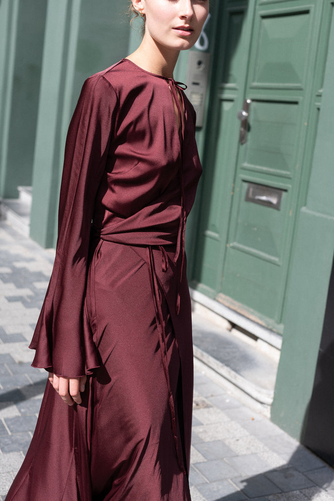 The Satin Dress 776 by ACNE STUDIOS has flared long sleeves, a side slit and asymmetric hem and closes with wrap tie ribbons at the waist
