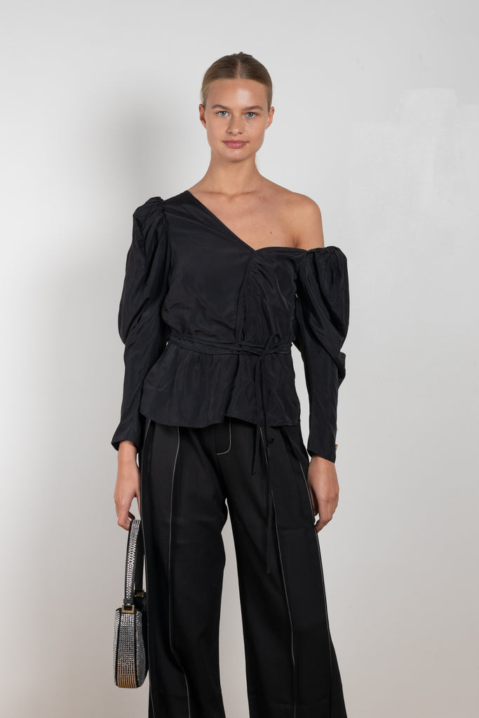 The Fiona Top by Rejina Pyo is a one-shoulder top with long puff sleeves, a tie detail to cinch the waist and exaggerated cuffs