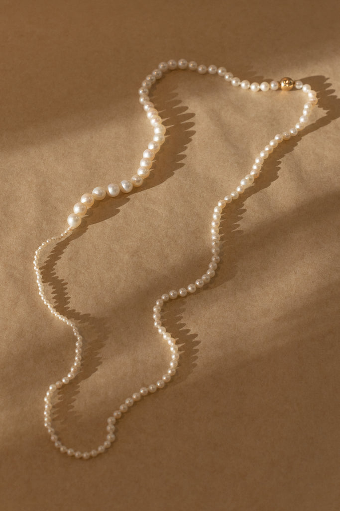 The Petite Peggy Perle Necklace is a longer version of the classic Petite Peggy Necklace with graduating sized Freshwater Pearls on an ancient Gold Lock
